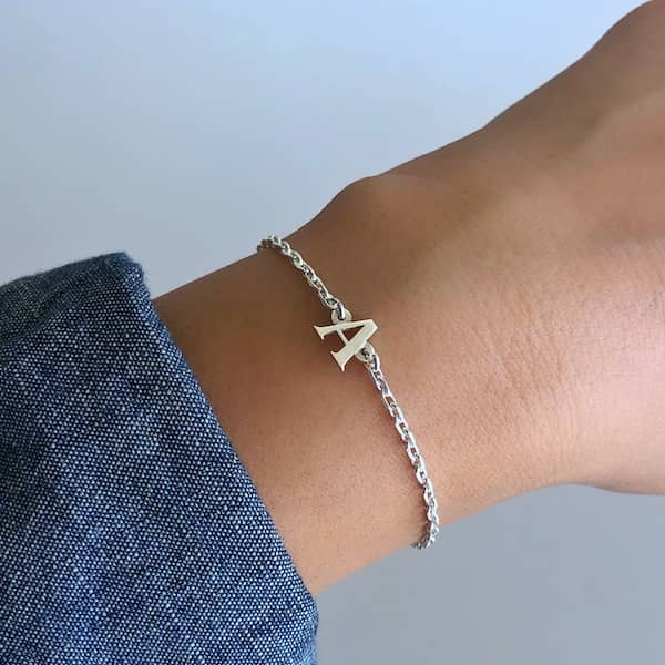 Pulsera cadena inicial plata en la muñeca, mostrando un diseño elegante con letra A de plata.
